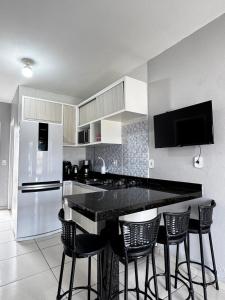 a kitchen with a black counter top and chairs at Casa em Imbituba SC, perto das Praias e Lagoa in Imbituba