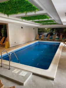 a swimming pool in a building with chairs around it at Kalisi Panorama Tornik in Zlatibor