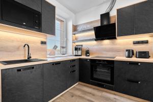 a kitchen with black cabinets and a sink at Rezidence George by Mountain ways in Kovářská +67 photos