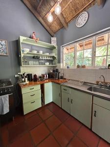 een keuken met een wastafel en een klok aan de muur bij The Little Thatch Cottage in Greyton