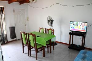 een eetkamer met een groene tafel en stoelen en een televisie bij Clau Propiedades in San Antonio Oeste