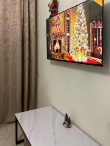 une télévision suspendue sur un mur avec un arbre de Noël dans l'établissement S-Van Cozy Home, à Sevan