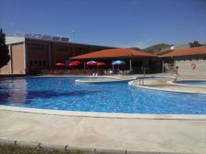 a large blue swimming pool with red umbrellas at Ramon del Xalet in Ibars de Noguera