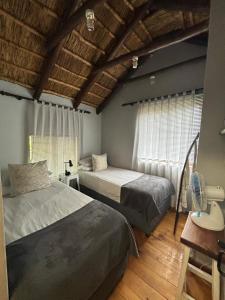 een slaapkamer met twee bedden en een raam bij The Little Thatch Cottage in Greyton