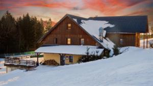 a barn in the snow with a sunset at Penzion Čekanka in Strážné