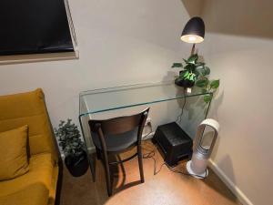 a glass desk with a chair and a lamp at A Sweet Studio for One in Altona