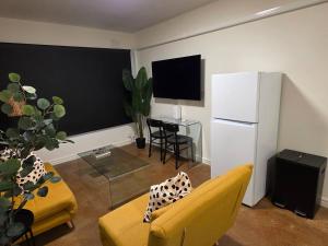 a living room with a yellow couch and a white refrigerator at A Beachside Villa with Vogue Verve in Altona
