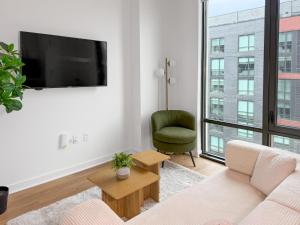 a living room with a tv and a green chair at The View - Navy Yard Washington DC in Washington, D.C.