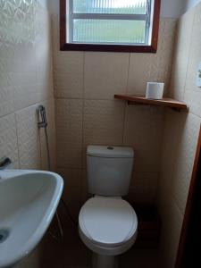 een badkamer met toilet, wastafel en raam bij Casa Amarela in Bocaina de Minas