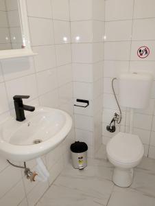 a white bathroom with a toilet and a sink at GuestHouse3 Karma369 in Plovdiv