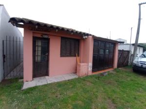 een klein roze huisje met een poort en een tuin bij Mono Julian in Quequén