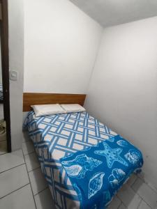 een kleine slaapkamer met een bed met een blauw dekbed bij Jacuípe House in Camaçari +6 foto's