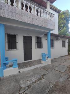 een wit huis met blauwe zuilen en een deur bij Jacuípe House in Camaçari