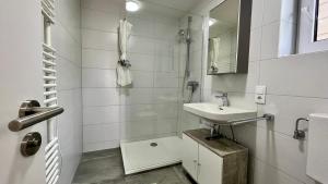 a white bathroom with a sink and a shower at Horizon Apartments in Memmingen