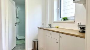 a white kitchen with a sink and a shower at Horizon Apartments in Memmingen +1 photo