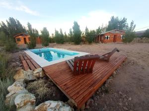 a swimming pool with a wooden deck and two chairs at Cabañas Angualasto in Uspallata