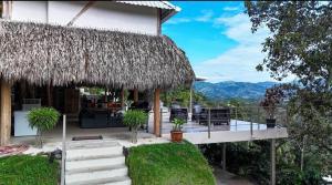 een huis met een rieten dak en een terras bij Silencio Verde in Atenas