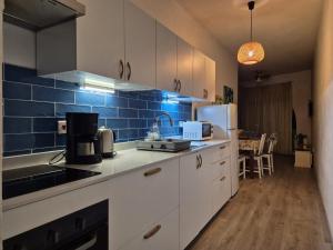 a kitchen with white cabinets and a blue tile wall at Excellent views in Marsalforn