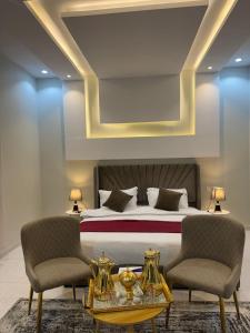 een slaapkamer met een bed met 2 stoelen en een tafel bij Holiday Home Al Taif Al Wisam in Taif