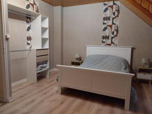 une chambre avec un lit blanc et un placard dans l'établissement Country apartment, à Orgelet