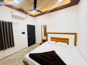 a bedroom with a white bed and a black door at Hotel Tathastu Inn in Ujjain