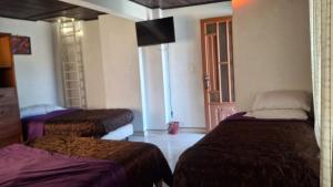 a room with two beds and a television in it at Cabaña el Rincon Del Lago in Paipa