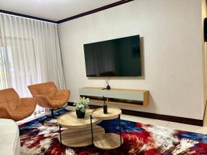 a living room with a couch and a tv on a wall at The Gentle Nest in Trevallyn