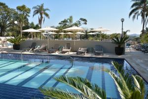 a swimming pool with chairs and umbrellas at a resort at Grand Resort Serra Negra in Serra Negra