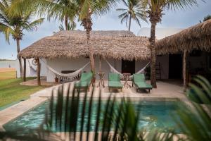 a hut with palm trees and a swimming pool at Kitenest in Itarema