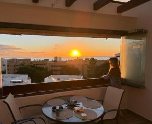 a woman looking out of a window at a sunset at AlaMar Cala Mijas Relax AlaMar Cala Mijas Relax - Sunny Premium Panoramic Sea Views SemiPenthouse in La Cala de Mijas