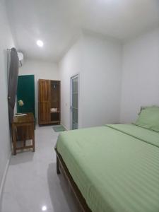 a bedroom with a green bed and a bathroom at Omah Barepan Temple View in Borobudur +3 photos