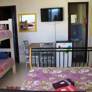 een kamer met een tafel en een bed en een televisie bij Joaquina 433 - Pousada Floripa in Florianópolis