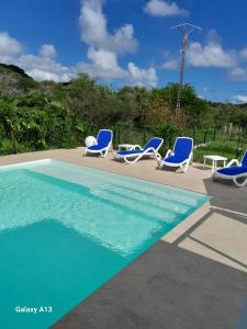 un groupe de chaises bleues et une piscine dans l'établissement LE DOMAINE de L'HYLODE, à Sainte-Anne