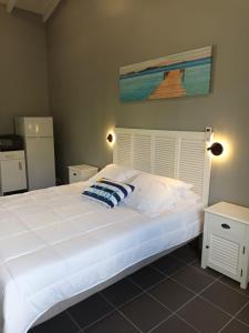 une chambre avec un grand lit blanc avec un tableau sur le mur dans l'établissement LE DOMAINE de L'HYLODE, à Sainte-Anne 20 autres photos