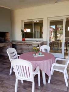einen Tisch mit weißen Stühlen und einem rosa Tischtuch in der Unterkunft Quinta Altos del Prado in San Nicolás de los Arroyos