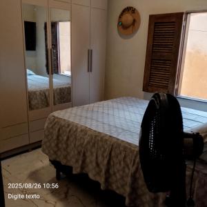 a bedroom with a bed and a chair and a window at Aconchego particular in Guaramiranga