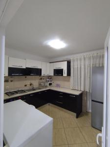 een keuken met witte kasten en een roestvrijstalen koelkast bij Acasă la Elias in Breb