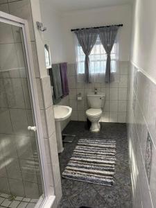 a bathroom with a toilet and a tub and a sink at Waaigras in Brackenfell +4 photos