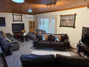 een woonkamer met lederen meubels en een flatscreen-tv bij Waaigras in Brackenfell