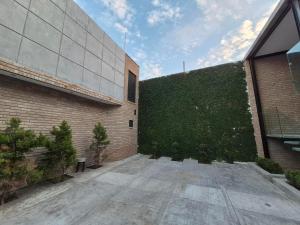 a building with a green hedge next to a building at Modern Industrial Artsy Apt Remodel Secure in Matamoros