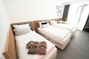 two beds in a hotel room with a robe on them at Das Naturlich - Ruhiges Apartment Hotel nahe Regensburg in Sinzing