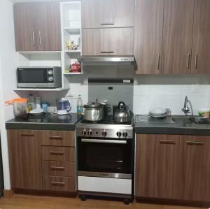 a kitchen with a stove and a microwave at Habitación Los Solises in Jauja