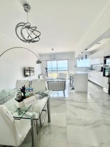 een grote witte woonkamer met een tafel en stoelen bij Departamento Pinterest Mar del Plata - Vista plena al mar con cochera in Mar del Plata