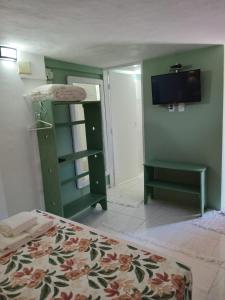 a bedroom with a bed and a tv on the wall at Suites Helena in Ilhabela