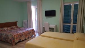 a hotel room with two beds and a television at Hotel Villa Etrusca in Marina di Campo