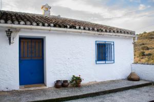 a white house with a blue door and potted plants at La Casita del Pastor in Loja