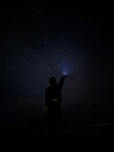a person pointing to the stars in the night sky at Hayaat siwa hot spring in Siwa