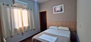 a small room with two beds and a window at Hotel Triangulo Itai in Itaí