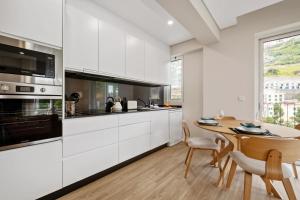 a kitchen with white cabinets and a wooden table at Modern Flat Just Steps From Shore in Ponta do Sol