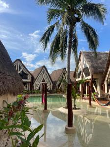 ein Resort mit einer Palme und einem Swimmingpool in der Unterkunft Kaaj Ndomi in Bacalar